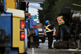 05 November 2012 - Workers attach cables to an overturned truck in preparation to position it back on its wheels, on Highway 99, in Surrey, B.C., Canada. While an investigation will take place, it is believed that the right front tire of the truck blew out, causing the truck to veer off the shoulder, rolling onto its side in a grassy area beside the highway. The driver was unhurt at the scene. Credit: Adrian Brown - N49Photo.