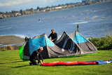 25 September 2013 - White Rock, B.C., Canada - Two men pack up their kiteboard equipment, as others fly their kites and kiteboard on East Beach, on the Semiahmoo First Nation reserve just south of the city of White Rock. Drayton Harbor and the US coastline in Washington State are seen in the distance. Photo Credit: Adrian Brown / Sipa Press.